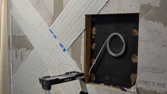 Shower wall prepared around plumbing openings.