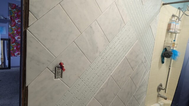 Bathroom floor tile being laid in a herringbone pattern.