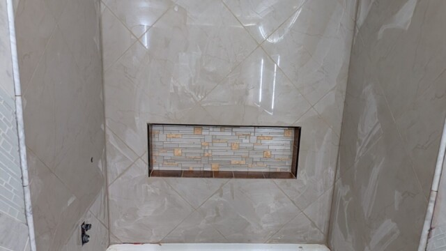 Tile installation progressing on the shower wall.