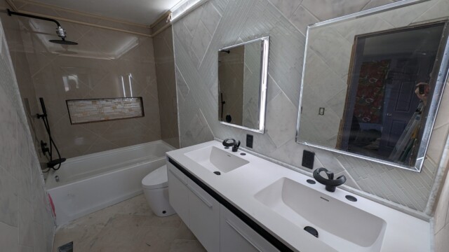 Finished vanity, mirror, and tiled bathroom wall.